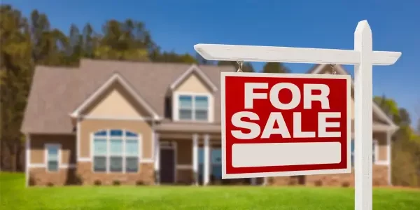 a for sale sign with a house in its background