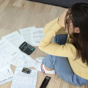 worried woman in front of piled up bills