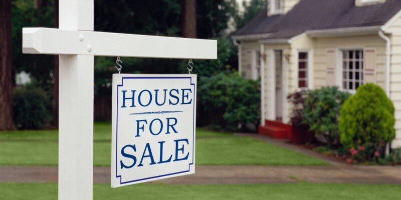 A house with a For Sale sign in front of it