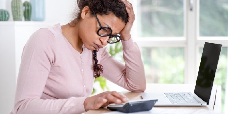 A person looking at a calculator with a worried expression