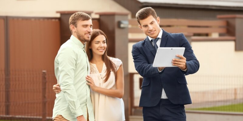 A real estate agent talking to a couple in front of a house