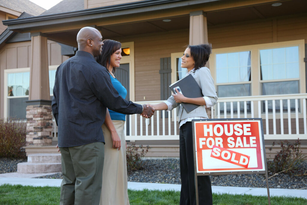 Illinois couple shake hands after selling house Young couple in Bloomingdale shake hands with realtor who sold their house.