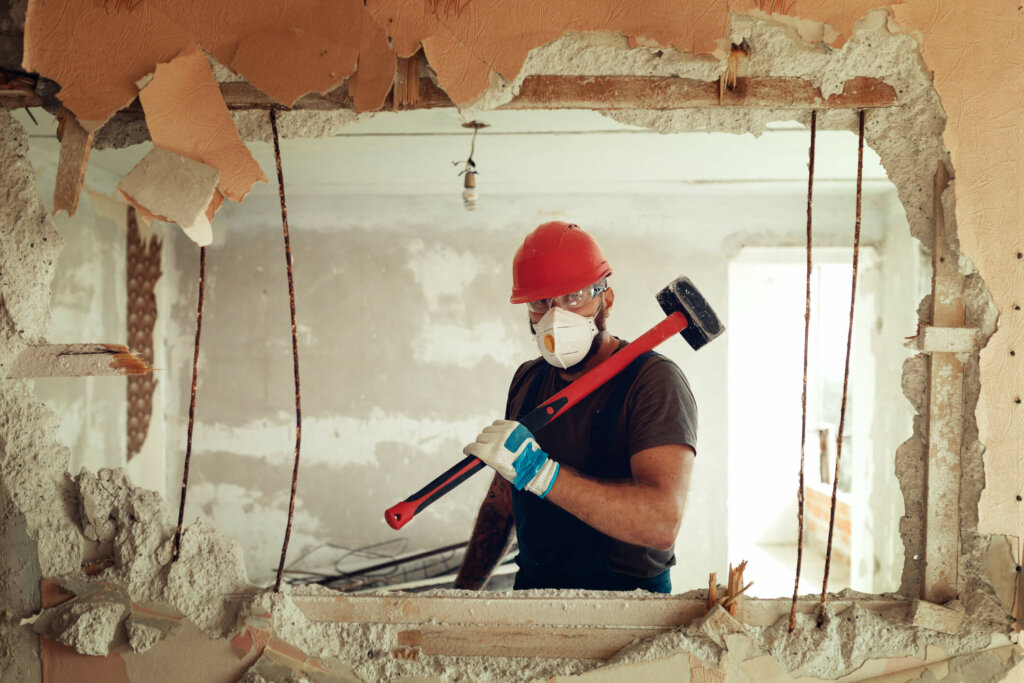 Learn about the different types of cash home buyers- including house flippers Illinois house flipper poses through wall he is tearing down in house he bought for cash
