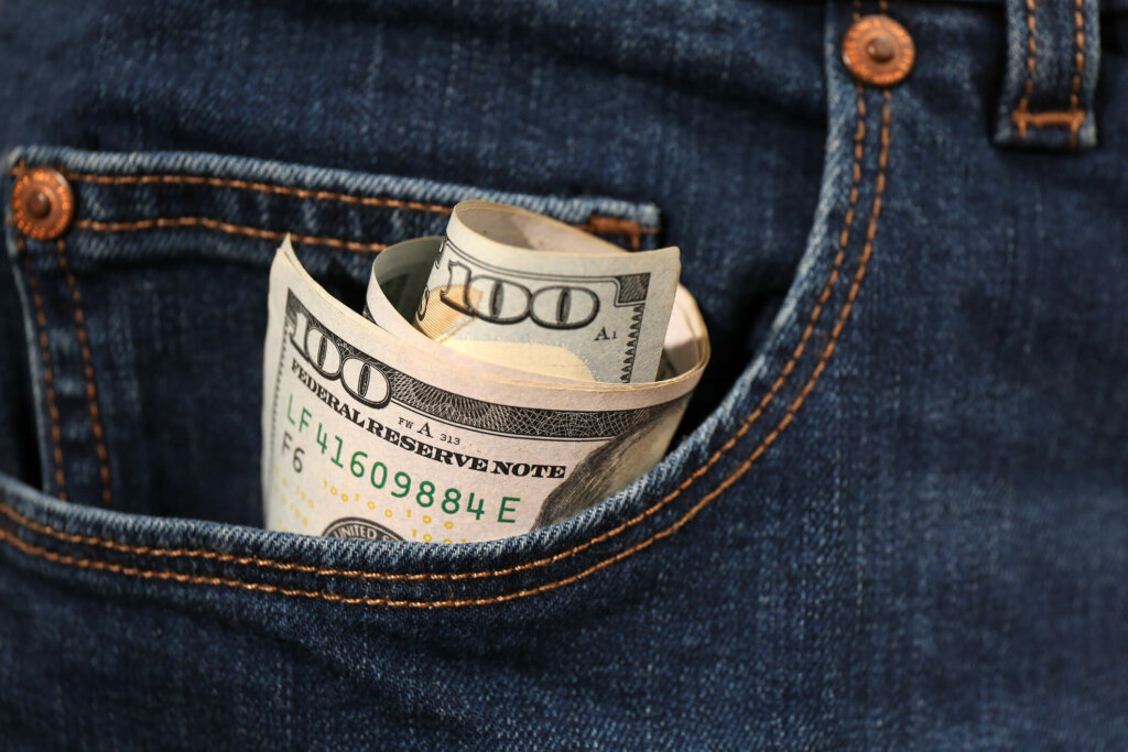 Learn how you can sell your house and save money without a real estate agent. American money bill in the pocket of Chicago homeowner.