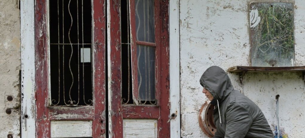 Squatter sitting at the porch of an abandoned house