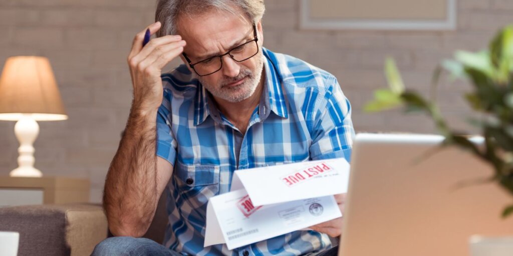 frustrated man looking at foreclosure bills