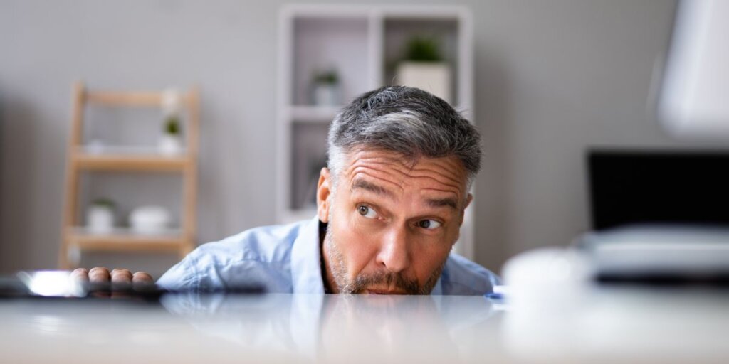 man hiding behind desk to avoid foreclosure