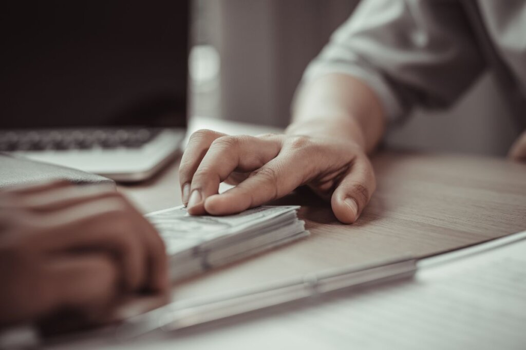 A close-up of hands exchanging cash across a table, symbolizing a quick home sale facilitated by REvitalize Property Solutions for a hassle-free transaction.