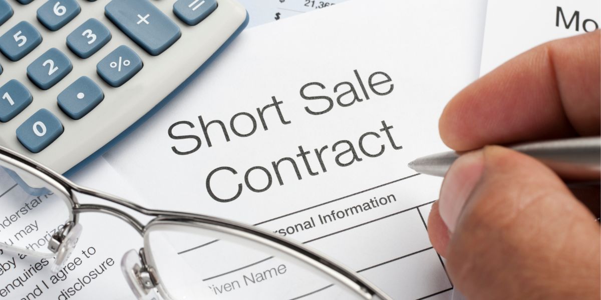 Short sale contract ready to be signed on desk with glasses and calculator.
