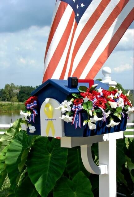 Blue house shaped mailbox with white and red flowers