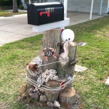 Mailbox on wooden posts decorated with net, rope, and nautical trinkets