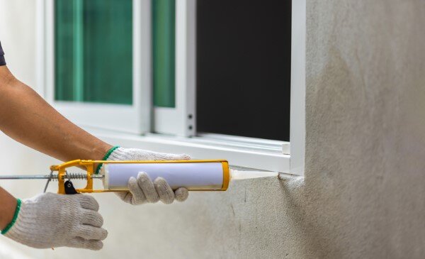 applying caulk to exterior window