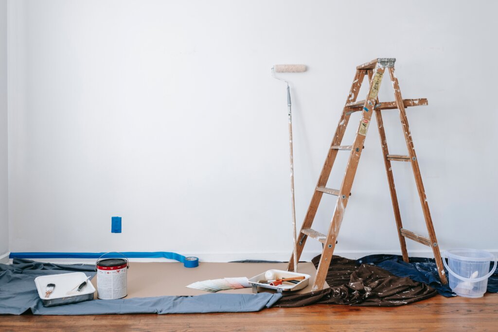 A clean room with a ladder and paint supplies with a fresh coat of white paint.