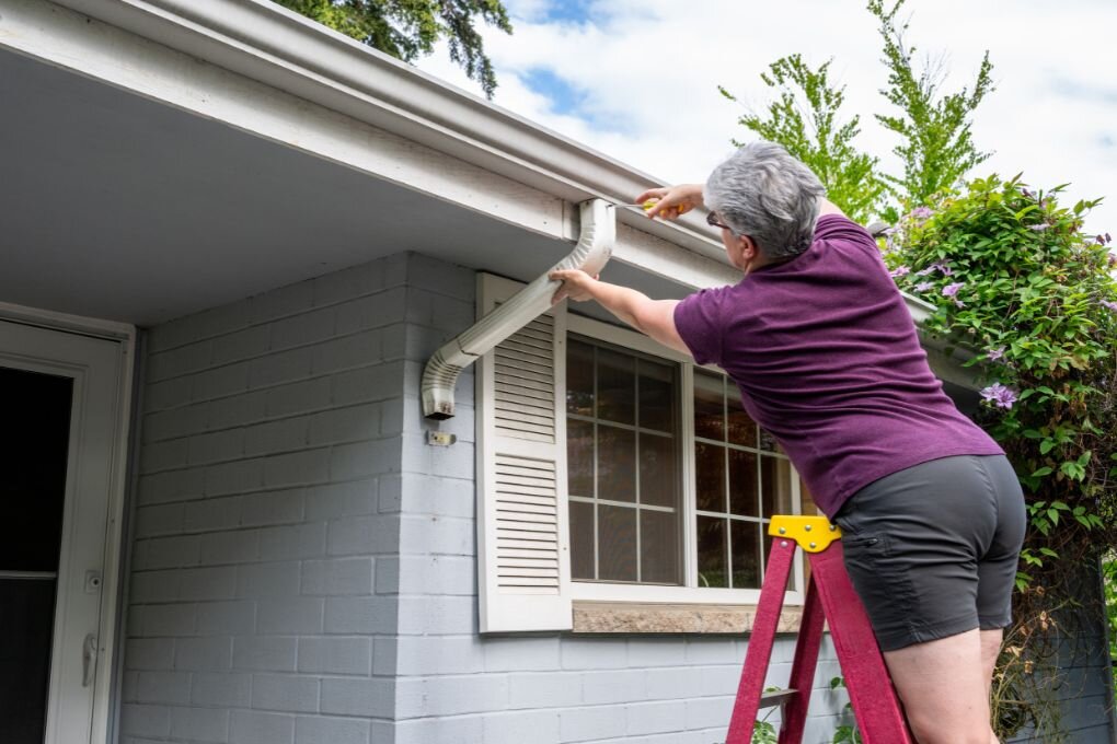 Woman fixing her gutters.
