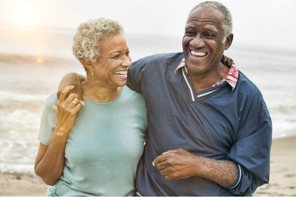 Old couple on a beach embracing.