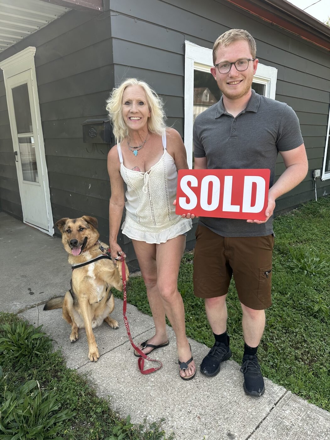 Celebrating a home sale with a SOLD sign and a dog.