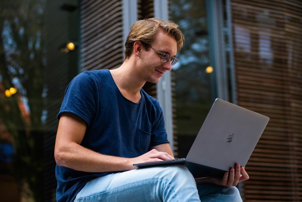 A person sitting outside and using a laptop