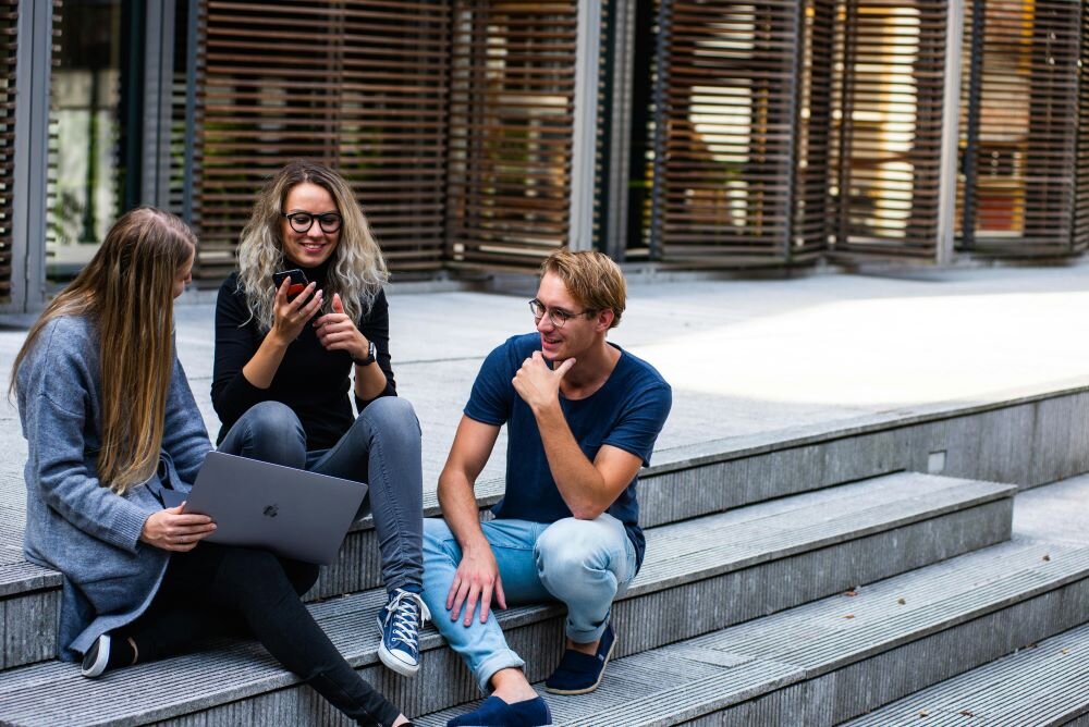 A group of college students sitting on the steps and discussing building wealth through property