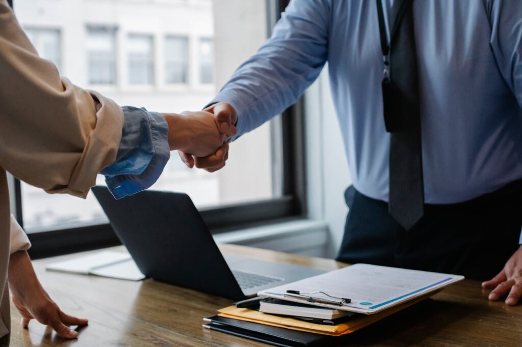 A man and a woman shaking hands in an office environment after closing a deal