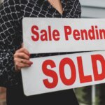Woman replacing a sale pending with a sold sign
