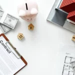 Contract, a miniature house and some coins on the table