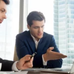 Two men having a discussion in front of a laptop