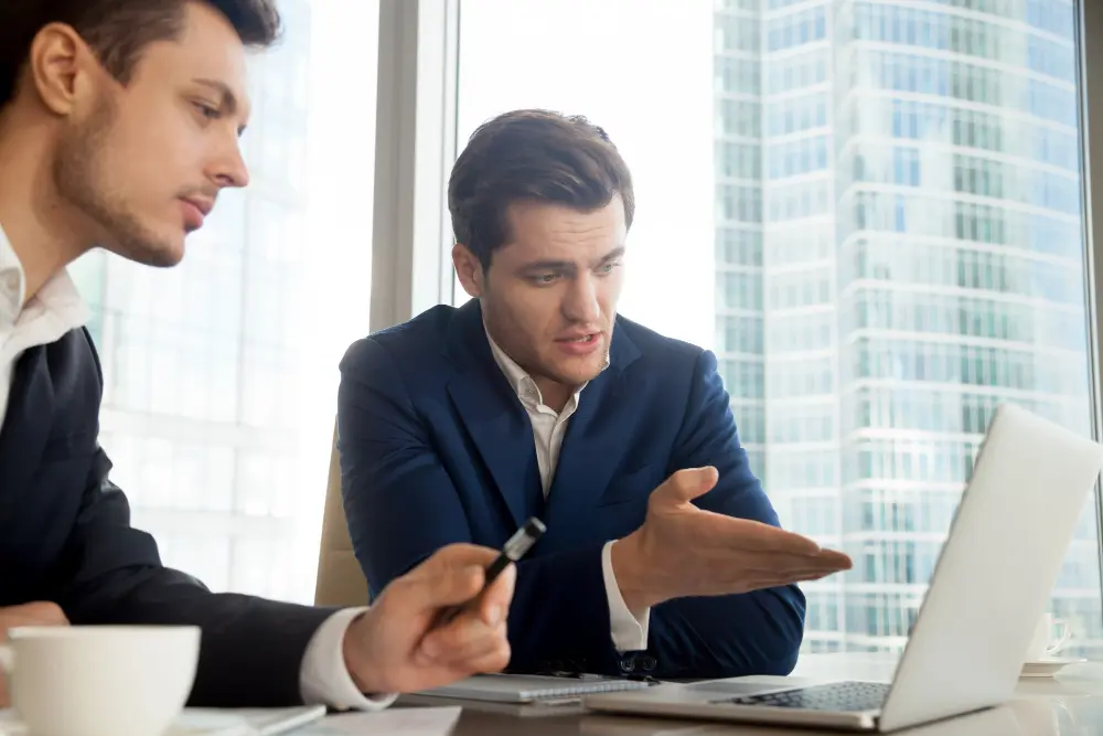 Two men having a discussion in front of a laptop