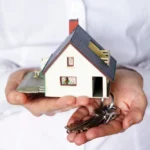 man holding a miniature house and key
