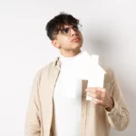 a man holding a piece of paper in his hands in the shape of a house