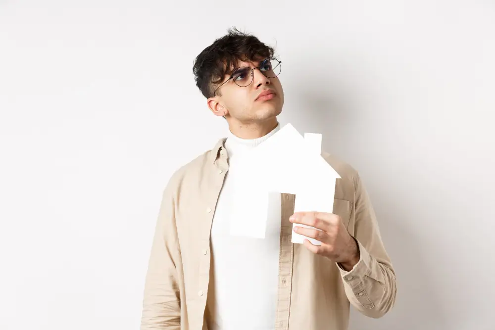 a man holding a piece of paper in his hands in the shape of a house