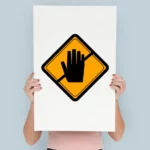 a woman holding up a sign with a hand on it