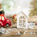 a small red car next to a small white house