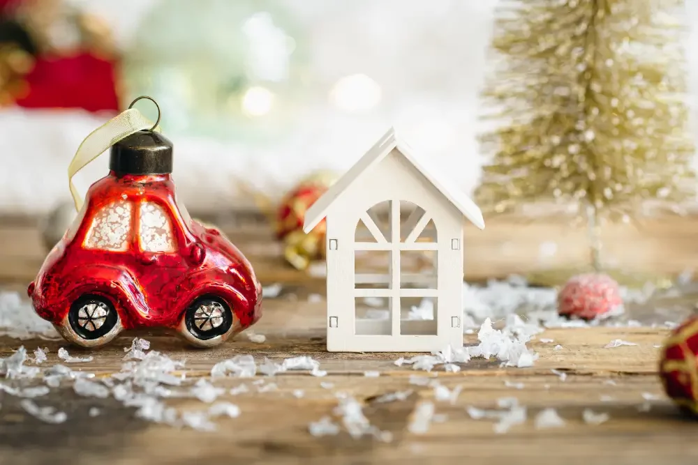 a small red car next to a small white house