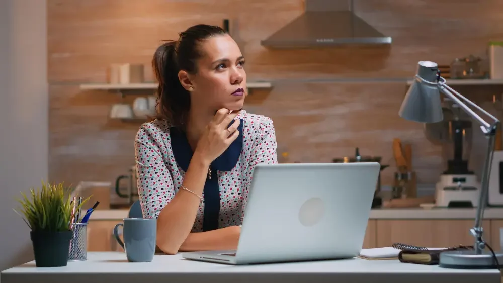 Woman thinking with laptop in front of her