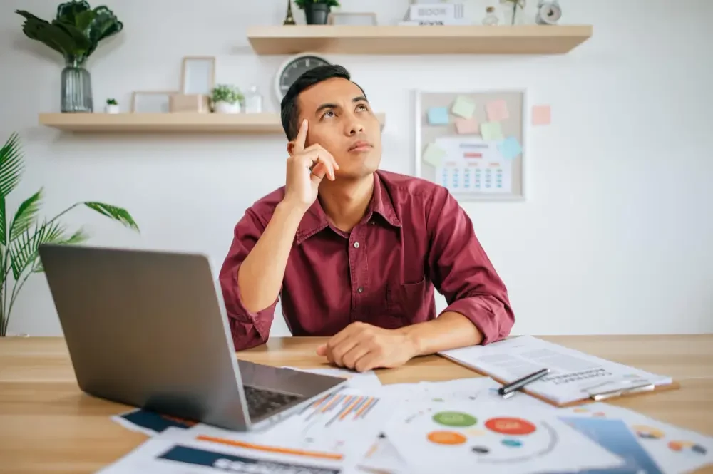 Man thinking with a laptop in front of him