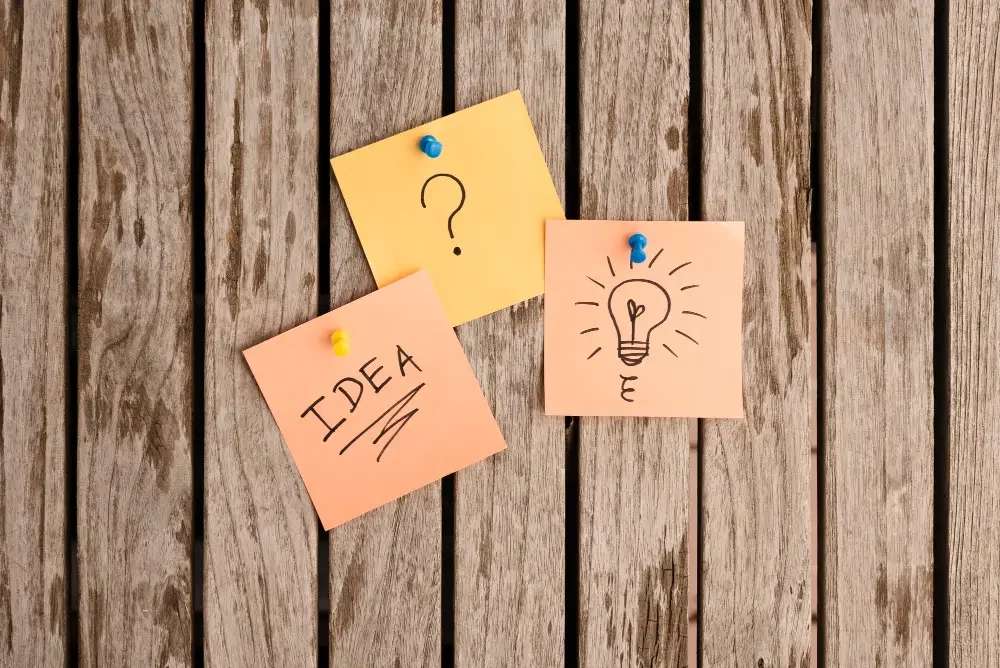 The word idea, question mark, and a light bulb on a post-it note.