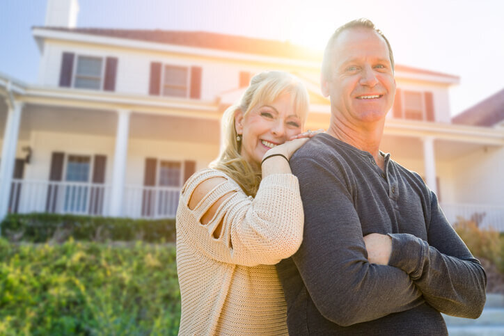 Attractive-Middle-aged-Couple-In-Front-Of-Their-House-selling-your-house-redmond-bend-prineville-bridgetown-home-buyers
