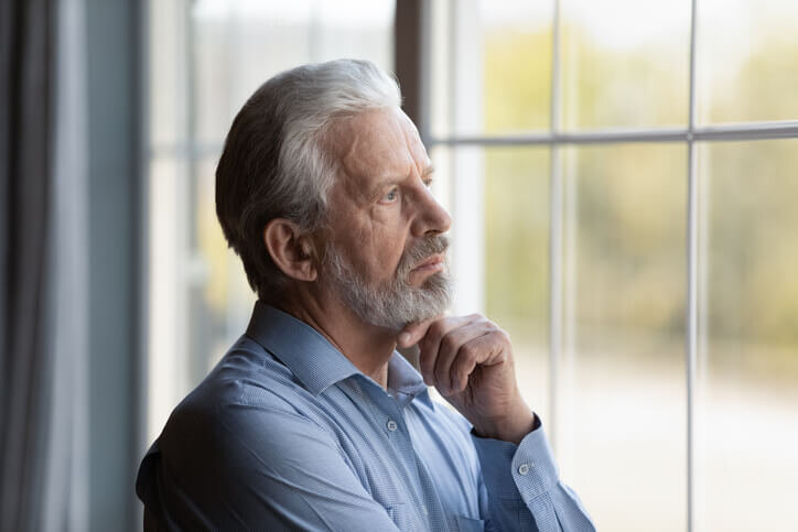 Head-shot-thoughtful-upset-mature-man-looking-out-window-divorce-and-sell-your-house-portland-vancouver-bridgetown-home-buyers