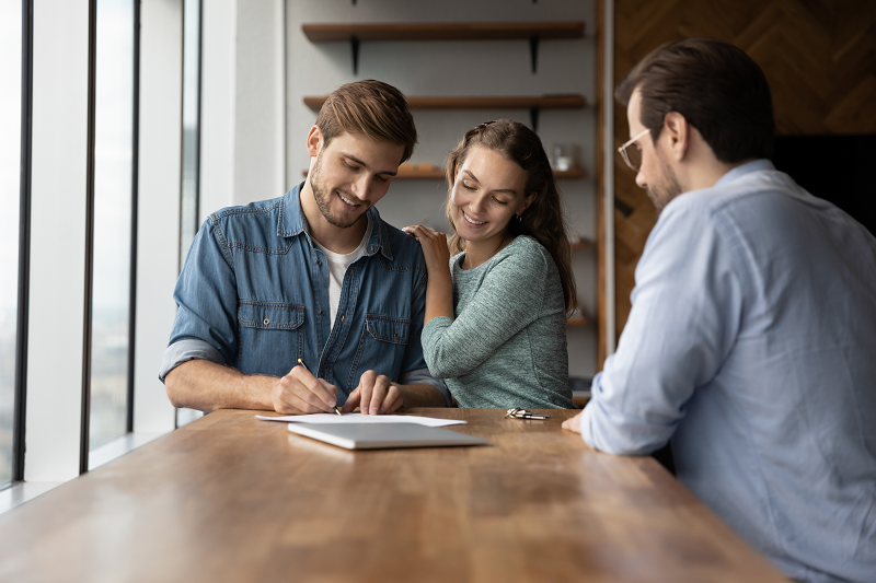 Photo of a young couple and a cash home buyer closing a deal on their home
