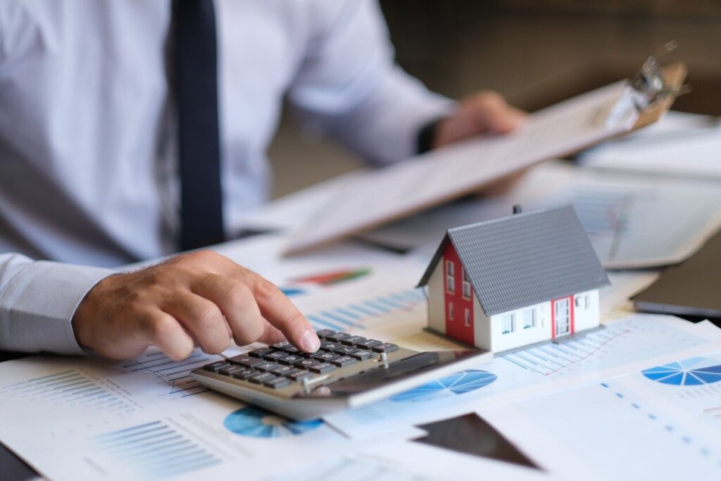 Houston homeowner calculating mortgage, tax, repair, and maintenance costs while deciding whether to wait or sell the house