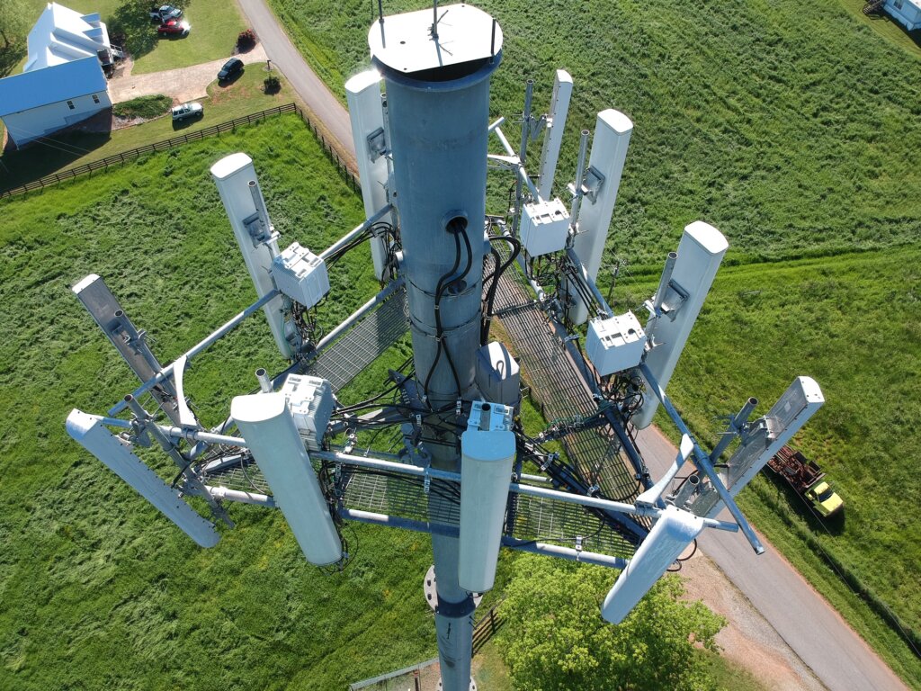 Looking for Cell Tower Lease Help? Close up drone photo of the top of a monopole cell tower. Call Tower Genius the cell tower lease consulting company that you can trust with your cell tower lease. Our number is 888-313-9750.