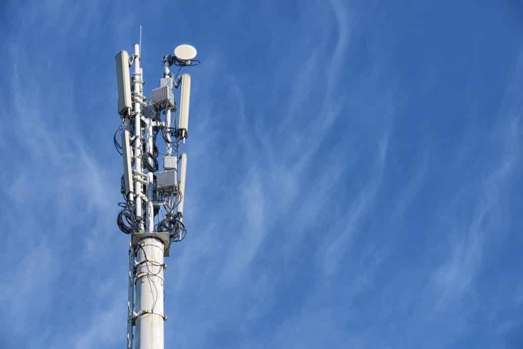 Black and white image of a cell tower monopole asking the visitor if they need assistance from a cell tower lease buyout expert? Tower Genius phone number provided is 888-313-9750.