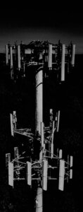 Large vertical black and white cell tower monopole picture on Tower Genius's cell tower lease buyouts page. Asking the question, what is my cell tower lease buyout worth?