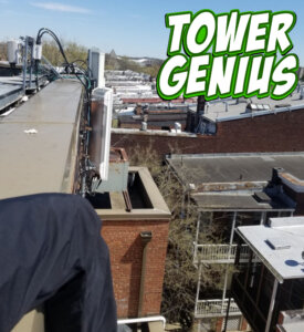Picture of rooftop parapet wall with cell site antennas and tower genius logo.
