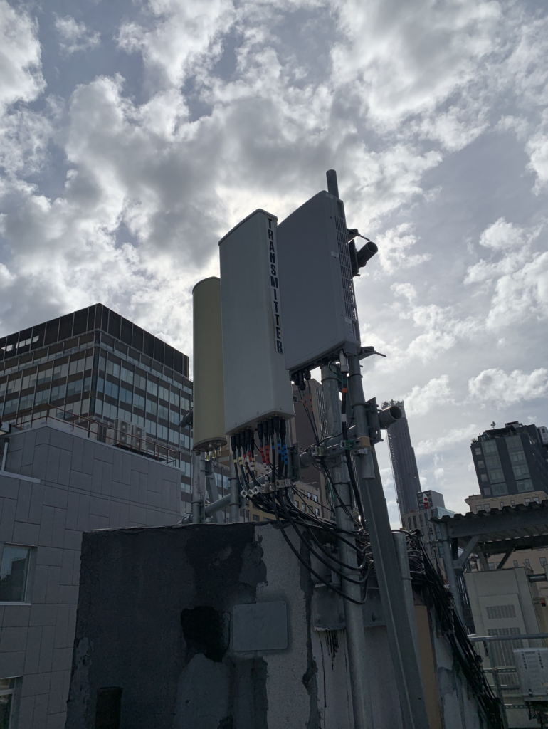 Rooftop Verizon cell site in Brooklyn NYC photo with tall building cityscape in background.
