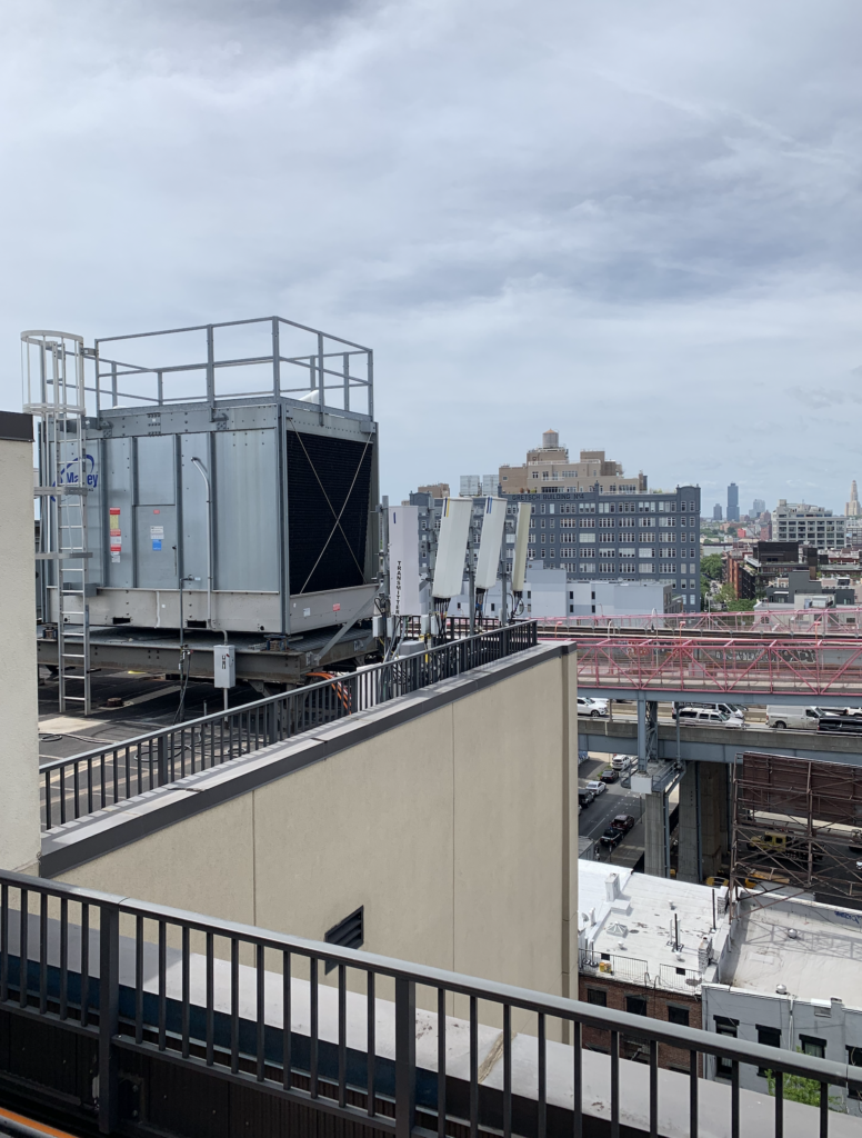 Rooftop cell site in Brooklyn NYC with antennas down tilted and generator on steel platform.