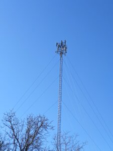 Image of a guyed wire cell tower with blue sky background