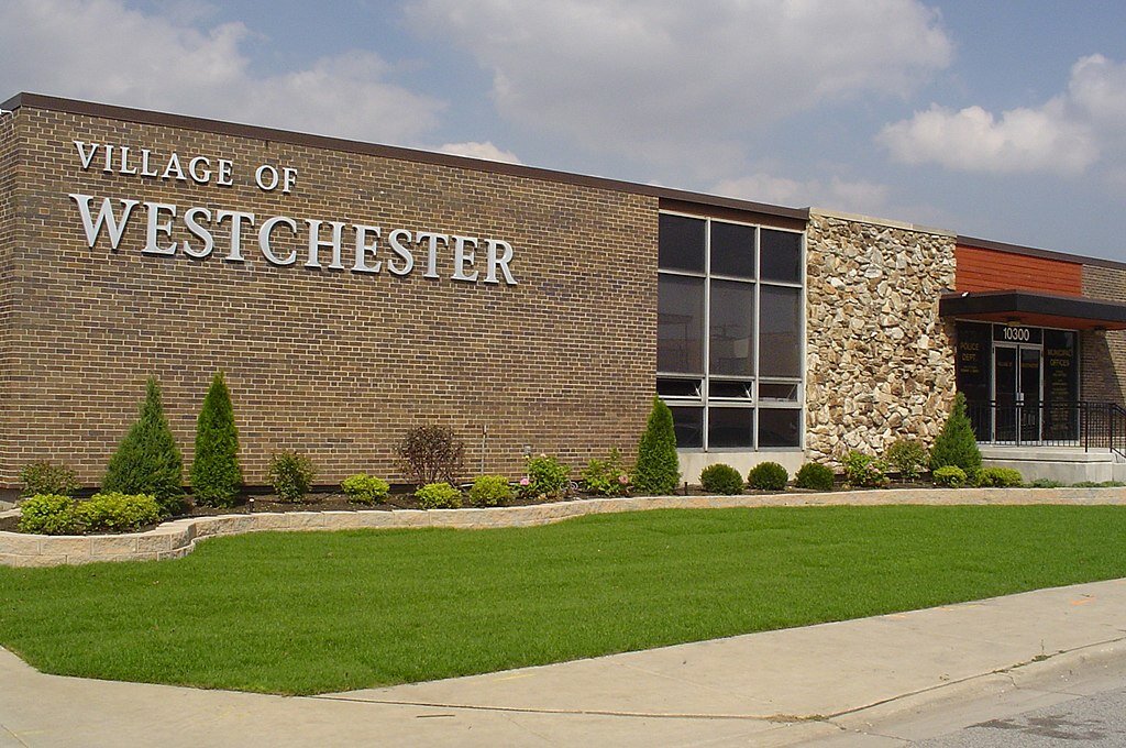Exterior sign of Village of Westchester in white letters over the brick exterior of the village hall