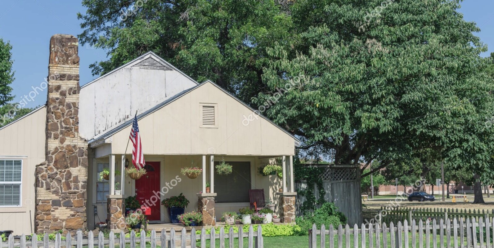 a modest house with american flag and picket fence