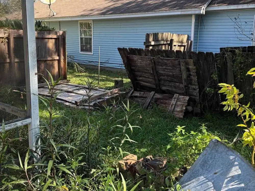 Wooden privacy fence blown down in a backyard after Hurricane Isaias
